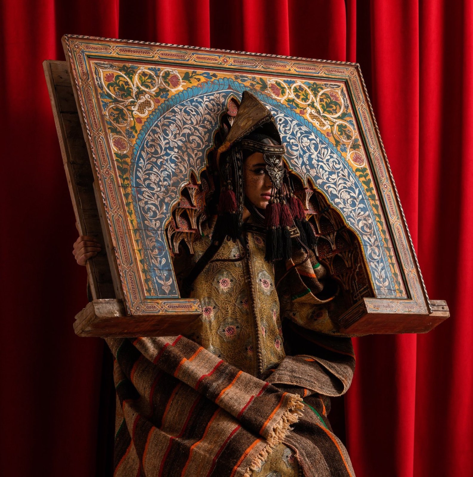 The Painted Arch — a hand-painted riad arch carried over a gilt kaftan, against red.