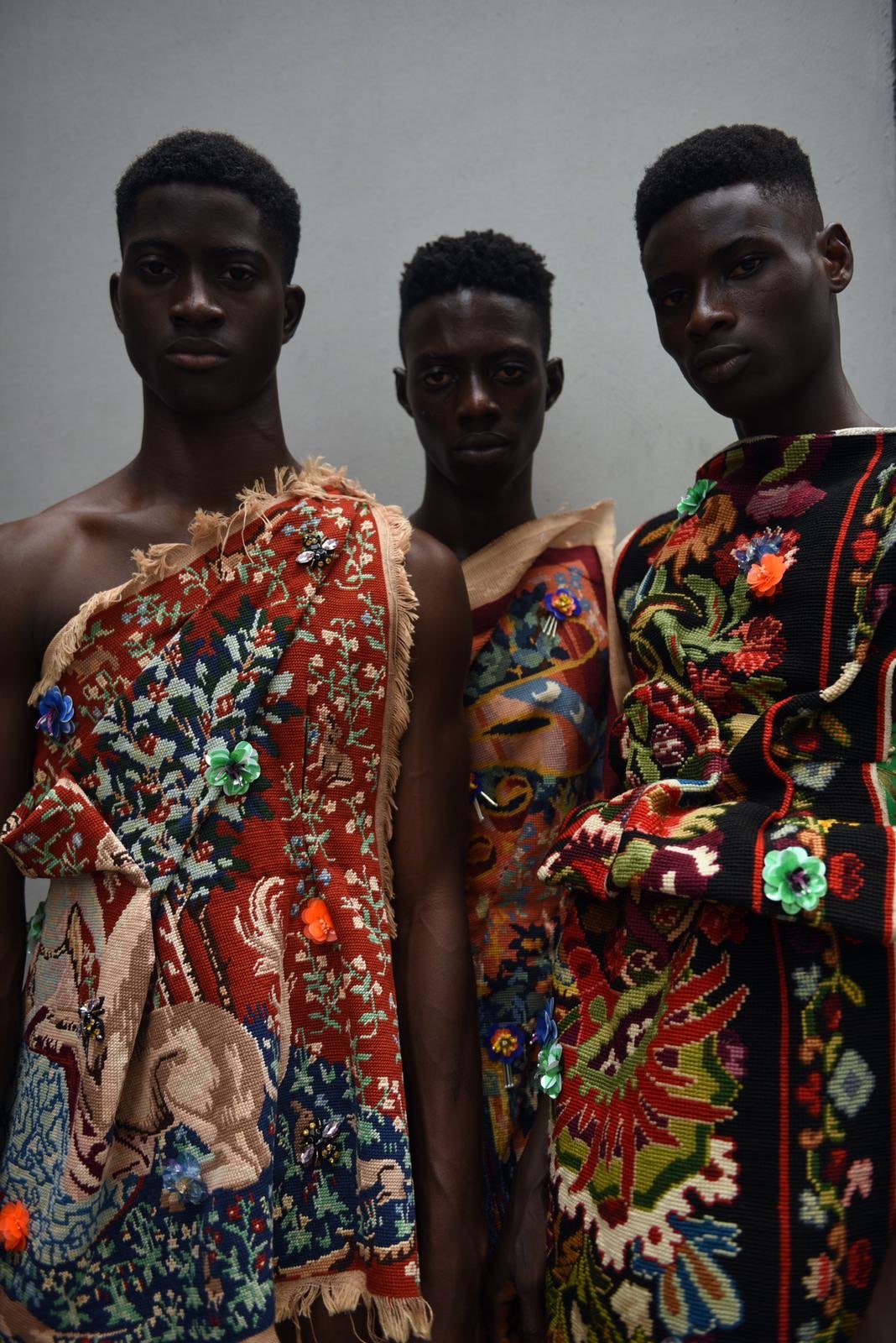 Three models in garments cut from vivid antique tapestries.